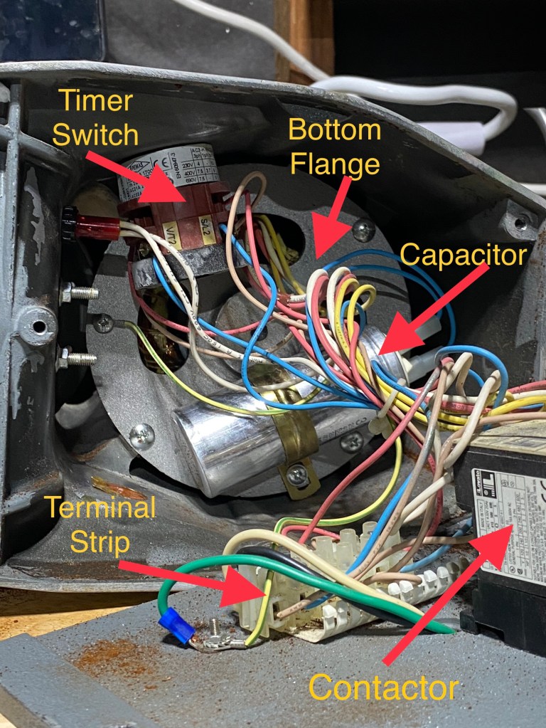 A view from the bottom of the Superjolly with the grinder's base plate removed and the terminal strip, contactor, timer switch, capacitor and bottom flange exposed.