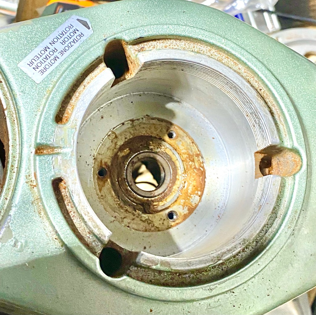 View from top of a Superjolly with the grind adjustment collar, upper and lower burr carriers, and bearing shield plate removed. An enormous amount of gunk had managed to accumulate, enough to both glue the shield plate to the burr chamber and also to wear out the bearing.