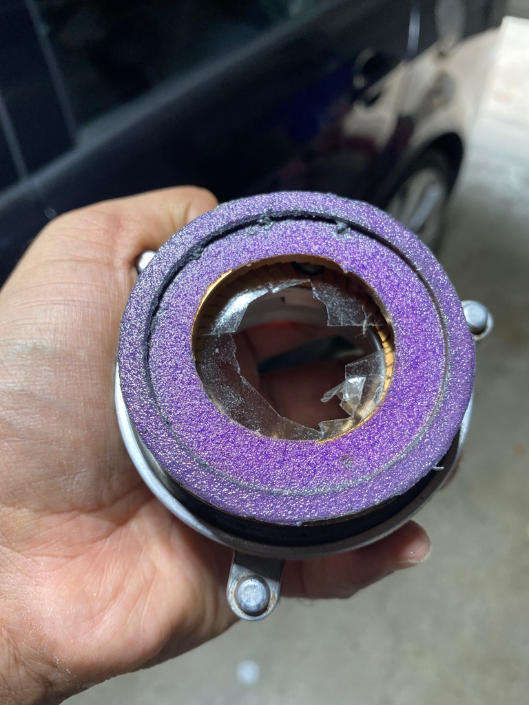 Figure 4: The upper burr carrier in a Superjolly with the upper burr screwed in and taped with double-sided tape to the lower burr, with sandpaper on the lower side of lower burr. This assembly stays static as the lower carrier is made to spin freely using the rotor shaft thus brushing against the sandpaper and eventually (hopefully) getting level against it. Sanded off particulates from the lower carrier can be seen stuck to the sandpaper.